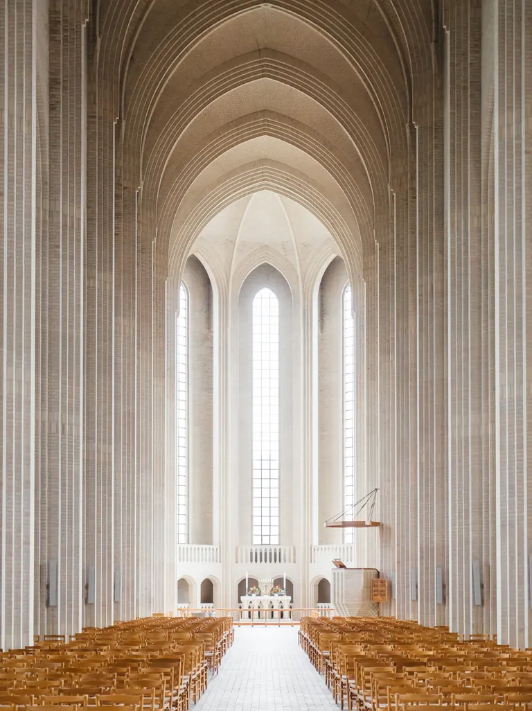 Daylight fills the vaulted nave of Grundtvig's Church above rows of wooden chairs.